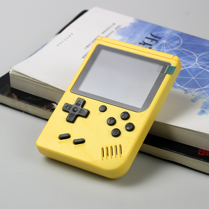 yellow handheld game console on books
